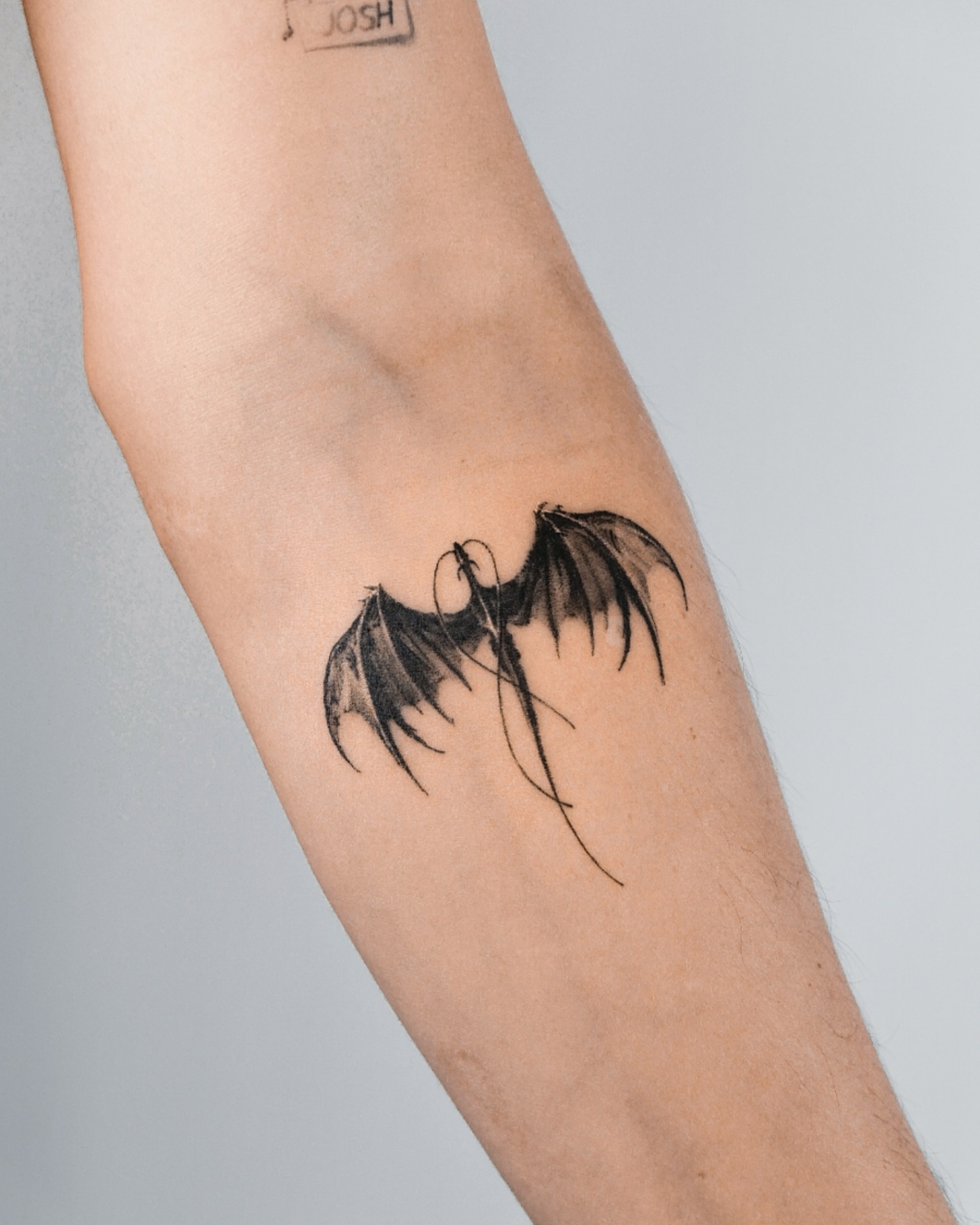 55. Title: Minimalist Dragon Wing Tattoo
